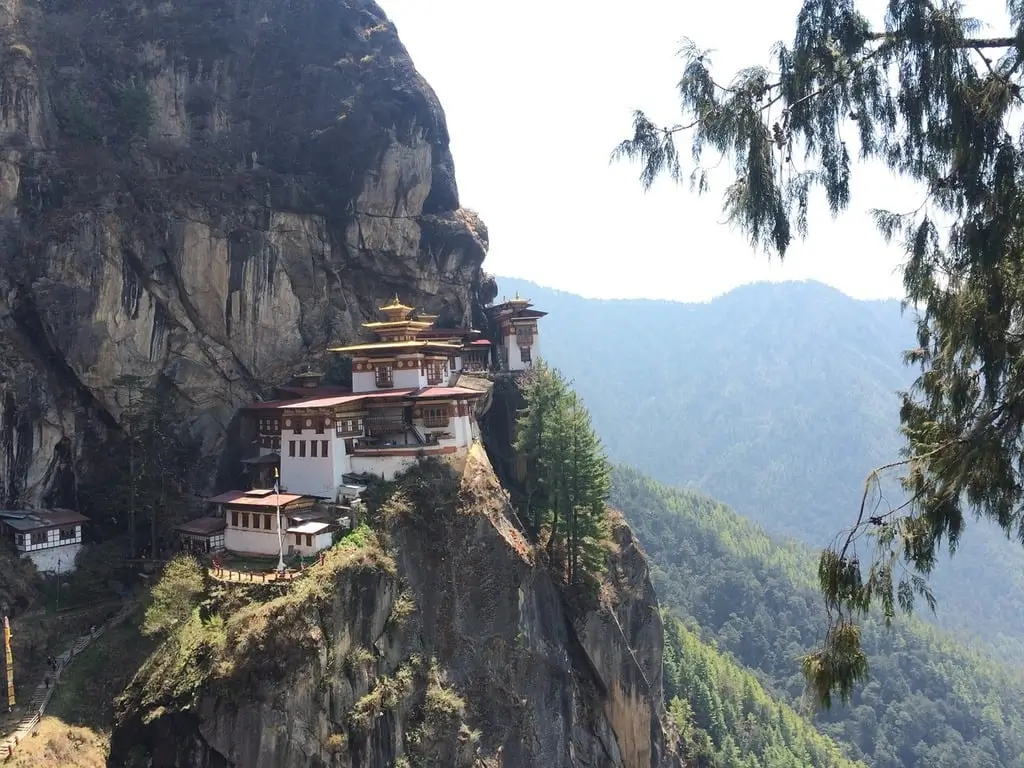 Tiger's Nest Monastery with white walls and red roofs, nestled in the mountains, a highlight of any trip to Bhutan.